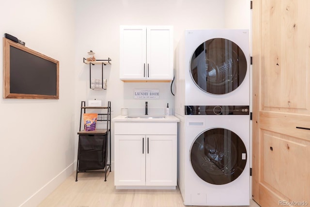 laundry room featuring cabinets, sink, and stacked washer and clothes dryer