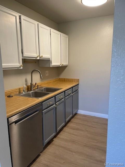 1415 Bacchus Dr Unit D9, Lafayette, CO 80026 - kitchen featuring stainless steel dishwasher, white cabinets, light countertops, and light wood-style floors