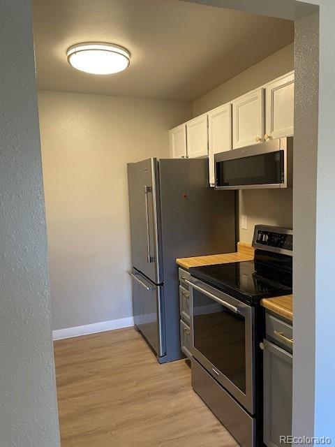 1415 Bacchus Dr Unit D9, Lafayette, CO 80026 - kitchen featuring appliances with stainless steel finishes, white cabinets, and light wood finished floors