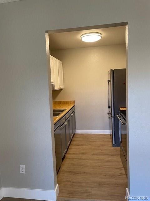 1415 Bacchus Dr Unit D9, Lafayette, CO 80026 - kitchen featuring light wood finished floors, white cabinets, light countertops, freestanding refrigerator, and stove