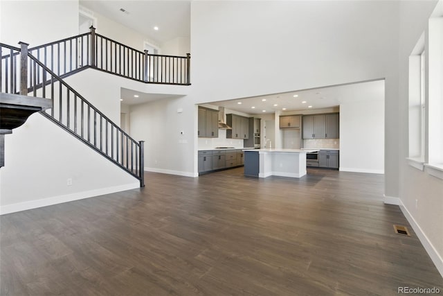 unfurnished living room featuring dark wood finished floors, stairs, baseboards, and visible vents