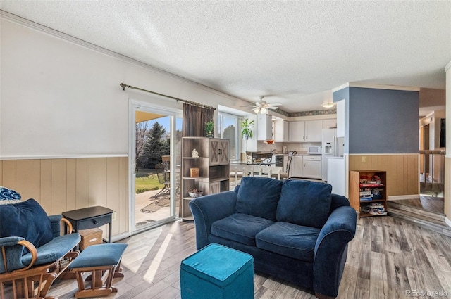 6735 E Lake Cir, Centennial, CO 80111 - living area with light wood finished floors, a textured ceiling, wainscoting, ceiling fan, and crown molding
