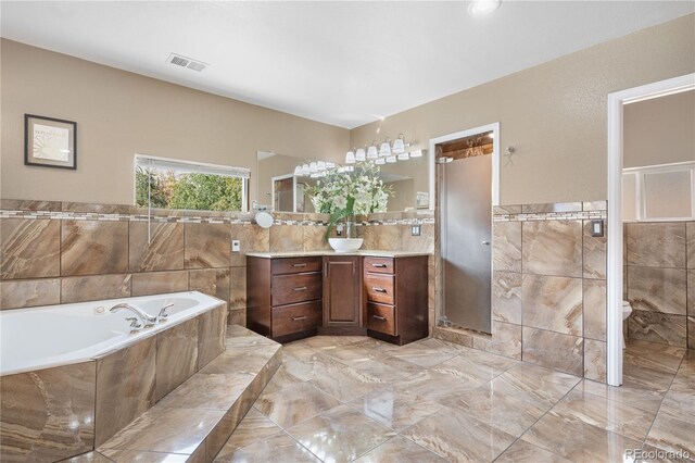 full bathroom with tile walls, vanity, shower with separate bathtub, and toilet