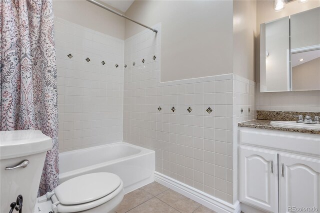 full bathroom with tile patterned floors, toilet, vanity, tile walls, and shower / bathtub combination with curtain