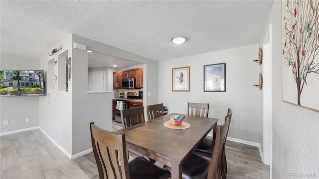 dining space with light hardwood / wood-style flooring and a textured ceiling