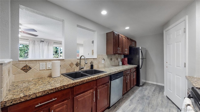 kitchen with backsplash, sink, appliances with stainless steel finishes, light hardwood / wood-style floors, and light stone counters