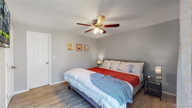 bedroom with a textured ceiling, light hardwood / wood-style floors, and ceiling fan