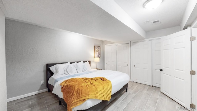 bedroom featuring light wood-type flooring and two closets