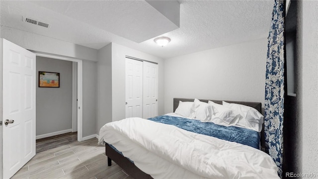 bedroom with a closet, light hardwood / wood-style flooring, and a textured ceiling