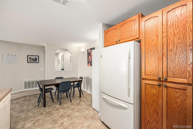 10818 Cimarron St Unit 206, Firestone, CO 80504 - kitchen with freestanding refrigerator, baseboards, arched walkways, and light floors