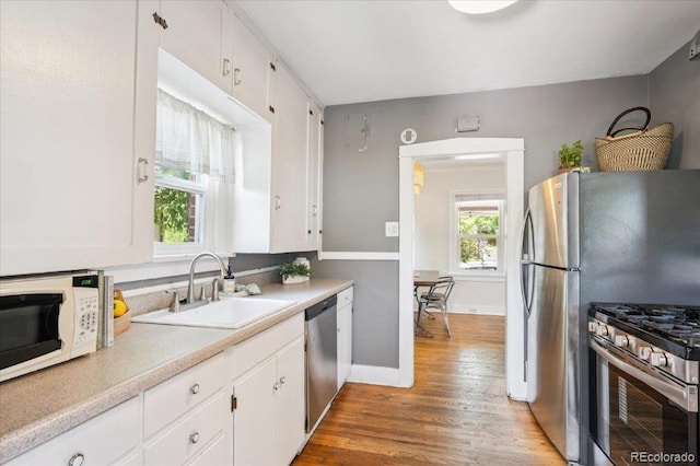 3622 Lowell Blvd, Denver, CO 80211 - kitchen with stainless steel appliances, white cabinetry, wood finished floors, and light countertops