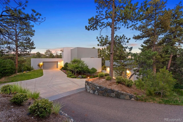 view of front facade with a garage, concrete driveway, and stucco siding