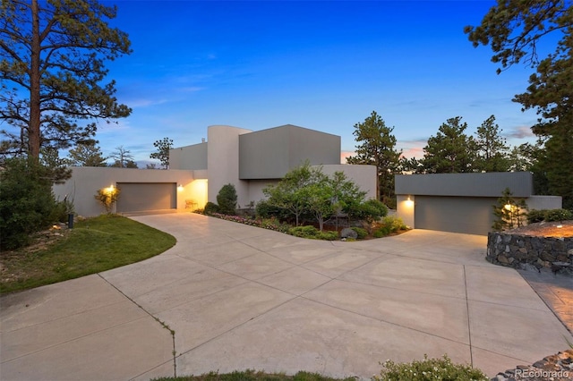 adobe home featuring a garage, concrete driveway, and stucco siding