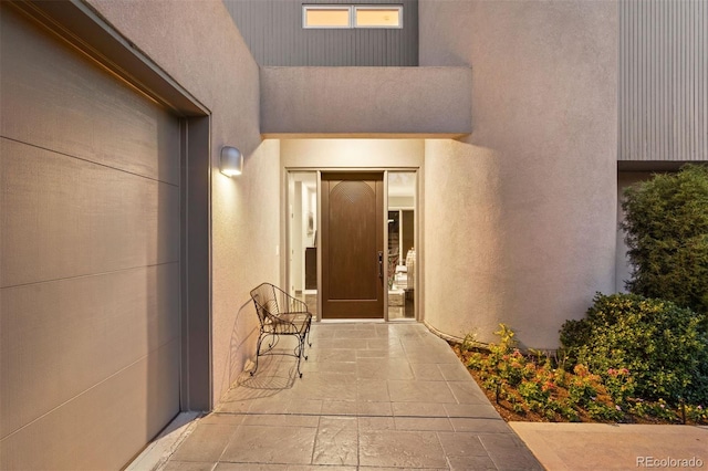 view of exterior entry featuring a patio and stucco siding