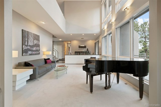 living area with carpet floors, visible vents, a high ceiling, and stairs