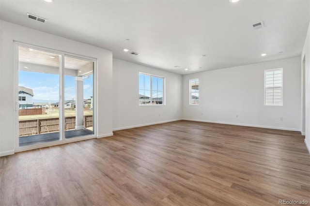 unfurnished room with visible vents, plenty of natural light, and wood finished floors