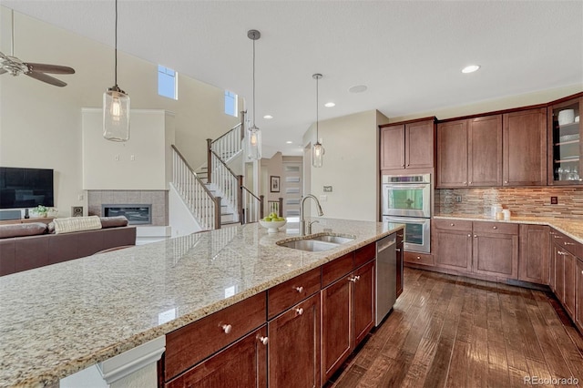 10365 Prairie Sky Pl, Lone Tree, CO 80124 - kitchen with appliances with stainless steel finishes, dark wood-type flooring, glass insert cabinets, a tiled fireplace, and ceiling fan
