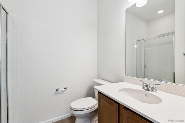 bathroom with toilet, wood finished floors, tiled shower, baseboards, and vanity