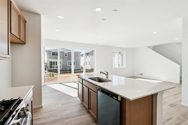 kitchen with dishwashing machine, light wood-style flooring, open floor plan, and a sink