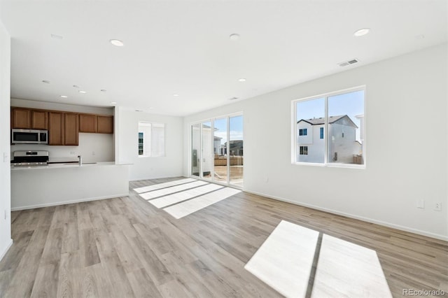 unfurnished living room with a sink, light wood-style flooring, and recessed lighting