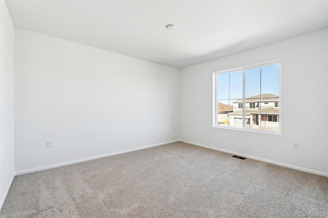 carpeted spare room with visible vents and baseboards