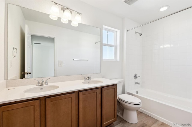 bathroom featuring a sink, shower / bathtub combination, toilet, and double vanity