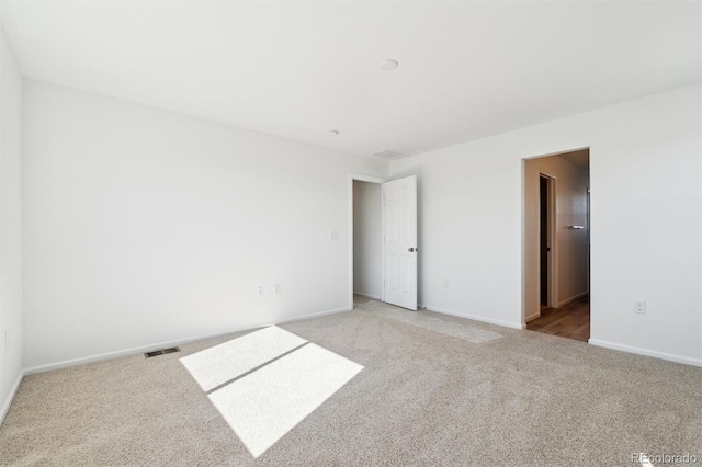 carpeted empty room featuring visible vents and baseboards