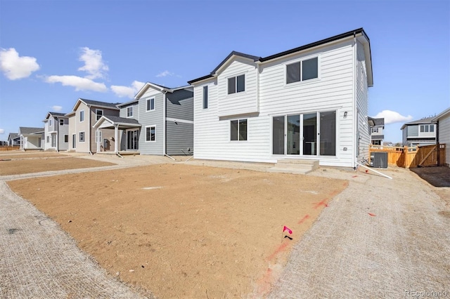 back of property with central air condition unit, a residential view, fence, and entry steps