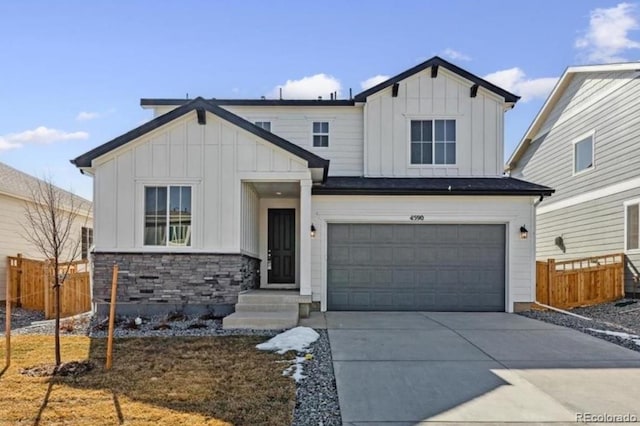 view of front of home featuring board and batten siding, fence, driveway, stone siding, and an attached garage