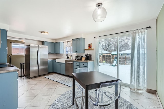 kitchen with appliances with stainless steel finishes, a wealth of natural light, sink, and light tile patterned floors