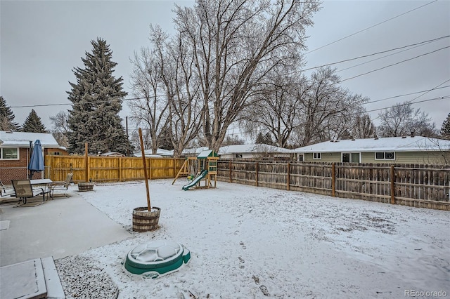 yard covered in snow featuring a playground