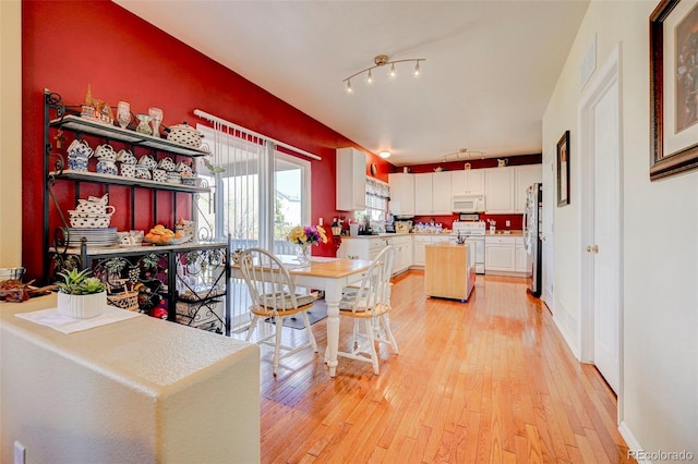 9172 Sunningdale Rd, Peyton, CO 80831 - kitchen with a center island, light countertops, light wood finished floors, white appliances, and white cabinetry