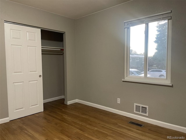 unfurnished bedroom with dark hardwood / wood-style floors and a closet