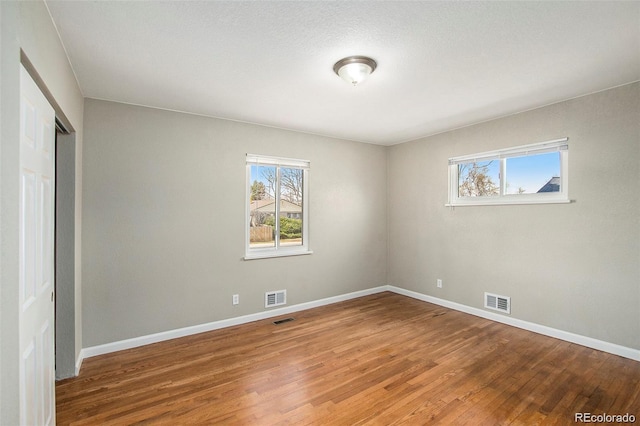 unfurnished room featuring plenty of natural light and wood-type flooring