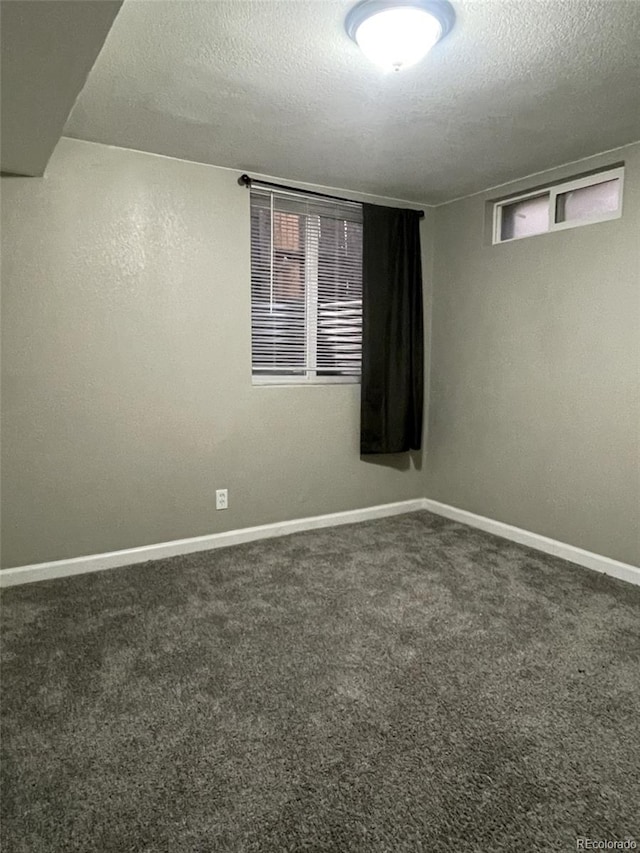 unfurnished room with a textured ceiling and dark colored carpet