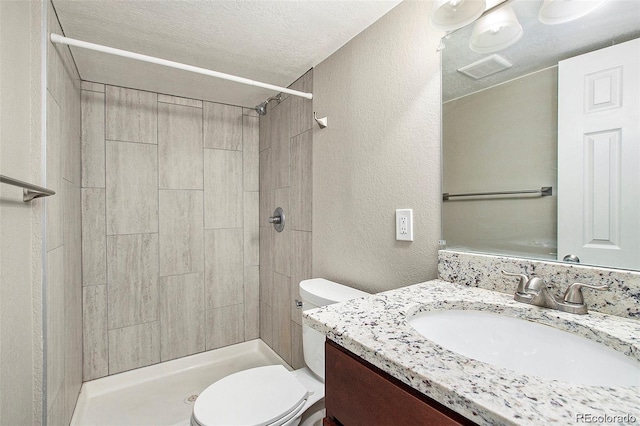 bathroom with vanity, toilet, a textured ceiling, and walk in shower