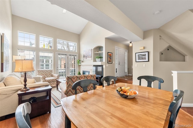 dining space featuring built in shelves, hardwood / wood-style floors, and lofted ceiling