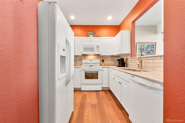 kitchen with tasteful backsplash, white appliances, sink, light hardwood / wood-style flooring, and white cabinets