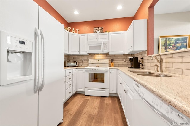 kitchen featuring decorative backsplash, sink, white cabinets, and white appliances