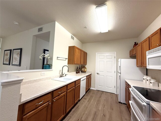 4451 S Ammons St Unit 108, Littleton, CO 80123 - kitchen with white appliances, brown cabinets, light wood-style flooring, light countertops, and a textured ceiling
