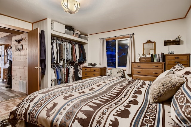 bedroom with crown molding, parquet flooring, and a closet