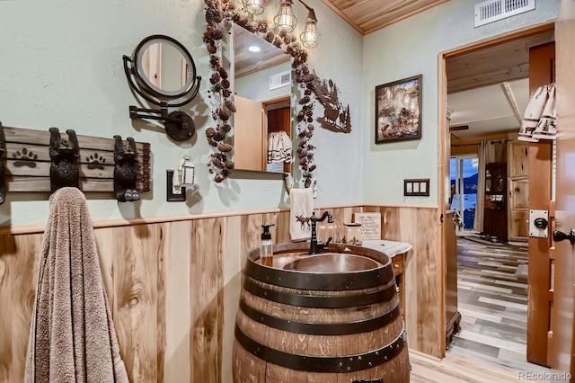 bar with crown molding, wooden walls, and light wood-type flooring