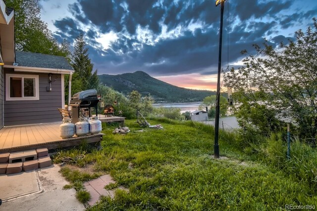 yard at dusk with a deck with mountain view