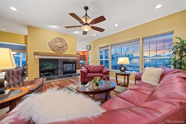 living room with a tiled fireplace, recessed lighting, baseboards, and wood finished floors