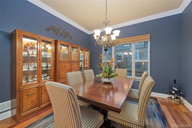 dining space featuring ornamental molding, wood finished floors, baseboards, and a chandelier