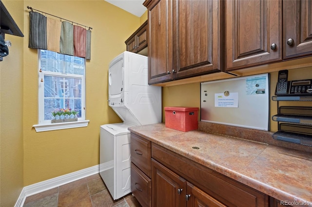 washroom with stacked washer / dryer, cabinet space, and baseboards