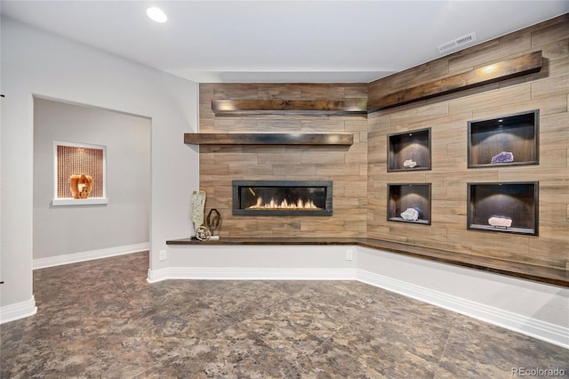 unfurnished living room with baseboards, visible vents, and a tile fireplace