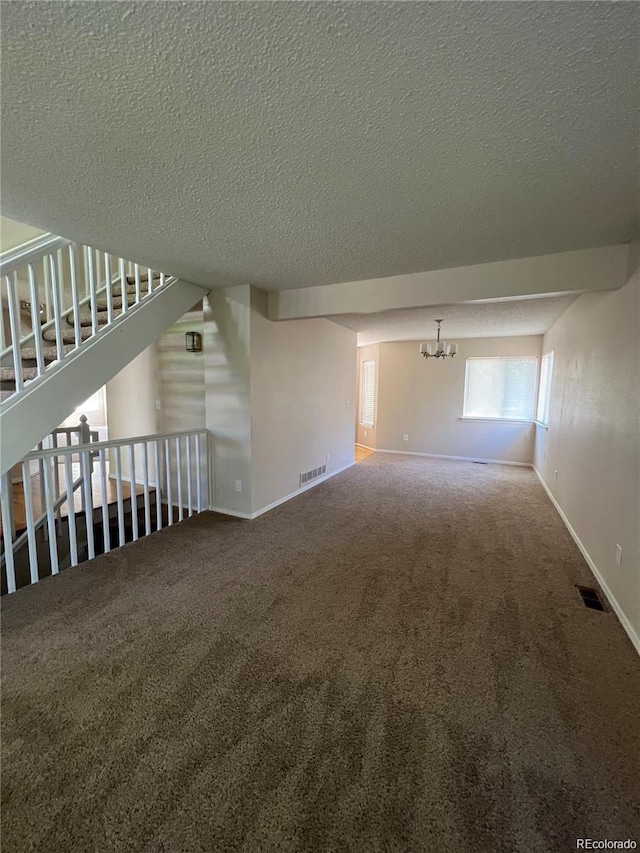 unfurnished living room with carpet flooring, a textured ceiling, and a chandelier