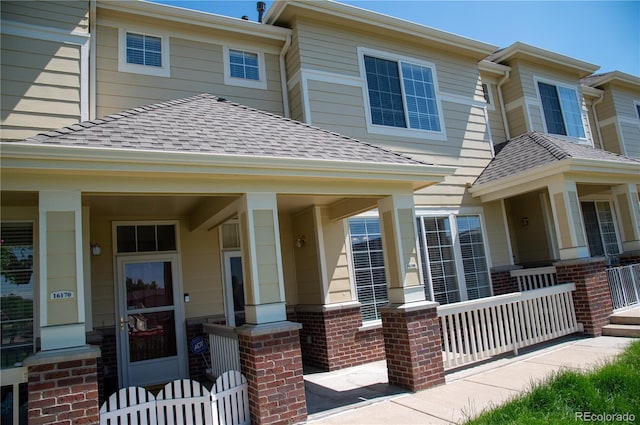 16180 E Geddes Ln Unit 14, Aurora, CO 80016 - view of front of house with covered porch, a shingled roof, and brick siding