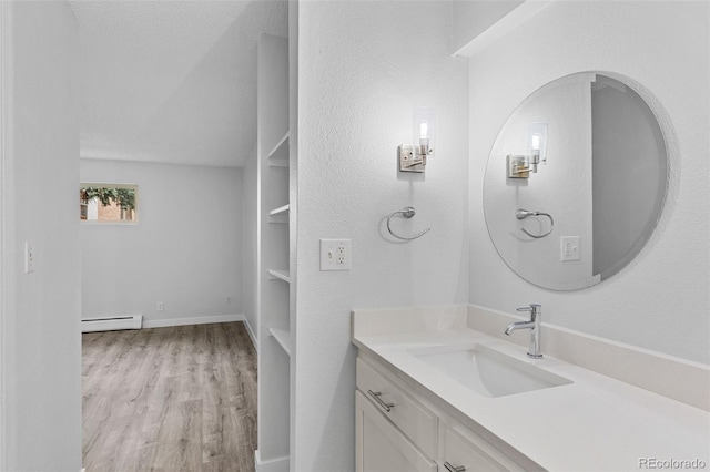 bathroom with a baseboard heating unit, baseboards, built in shelves, vanity, and wood finished floors